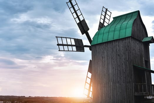 Old windmill standing alone in the field with the blue sky on the background with copyspace