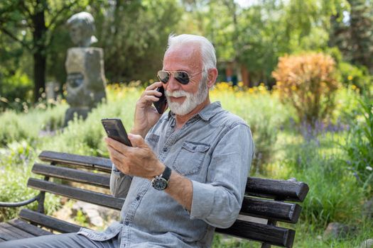 Old man compare two smartphones