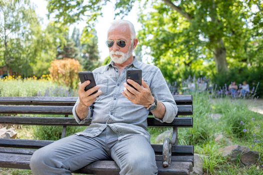 Old man compare two smartphones