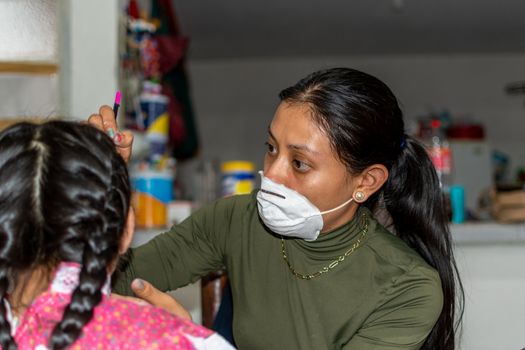 mother putting makeup of Catrina on her daughter's face to celebrate a festival