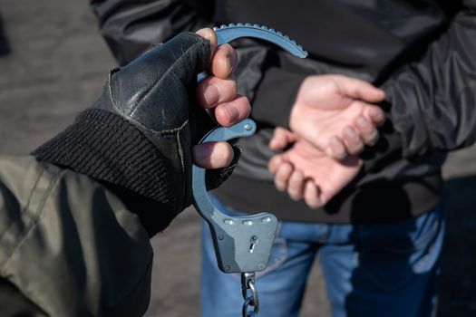 arrest of a criminal, a police officer puts handcuffs on the hands of a bandit