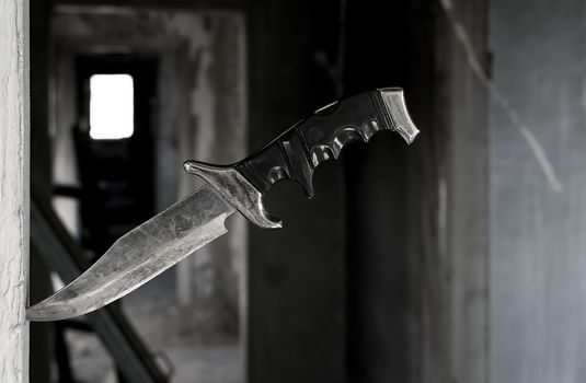 terrible fighting old knife stuck in the doorway on the background of the ruined corridor of the old abandoned house
