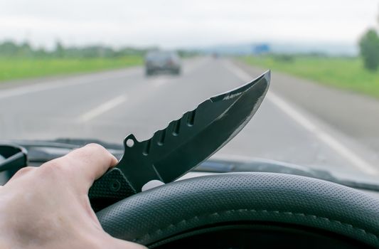 Crime, man, driving a car holding a knife, riding on the road