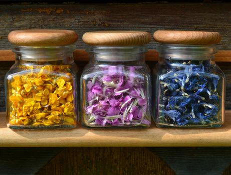 Small transparent glass jars with colored flowers