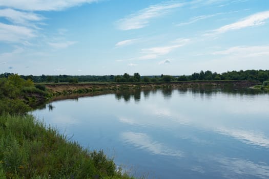 view of the river among the shores covered with forest and shrubs on a sunny summer day