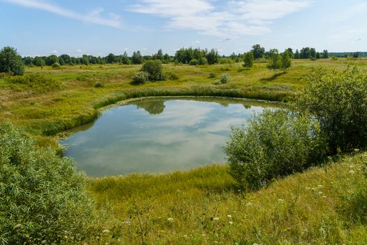 A small round lake among floodplain meadows and forests