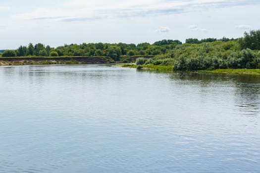 calm plain river among the banks covered with forest under a cloudy sky