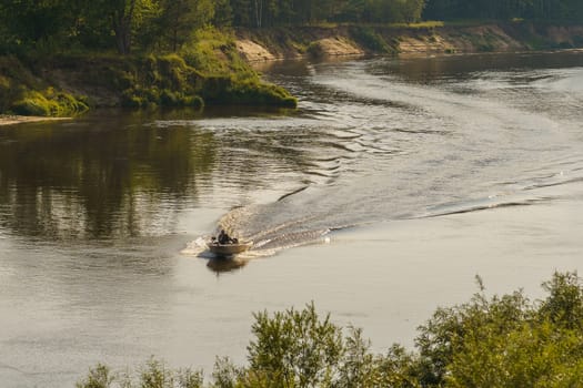 riverbank and a motor boat goes on the water, leaving a mark