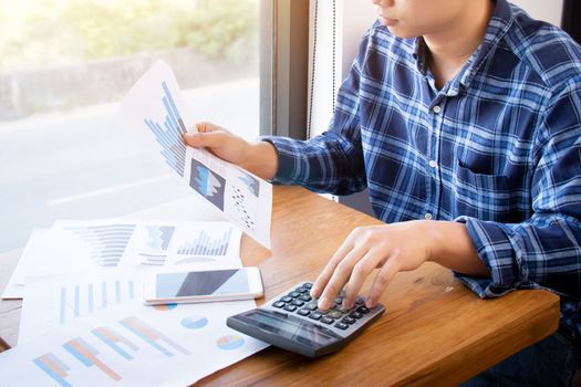 Business accounting people, saving, finance and economy concept. Serious Asian businessman using calculator for calculations documents , charts and graphs. Asia male model in his 30s