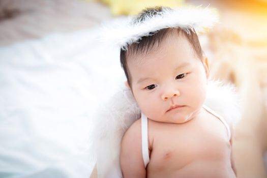 Close-up beautiful newborn baby girl. A portrait of a beautiful newborn baby girl wearing angel wings and angel ring.