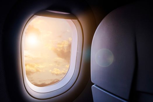 Clouds and sky with golden sunlight and lens flare as seen through window of an aircraft