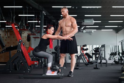 Personal trainer coach instructor athlete sportive man woman gym Boyfriend girlfriend training together Middle adult handsome sportsman people fitness exercising indoors. squats