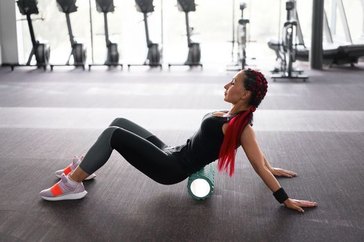Woman massaging foam roll leg gym myofascial release exercise rolling, trigger points Middle adult caucasian woman sportswoman uses roller massager for relaxation, stretching muscles and back pain.