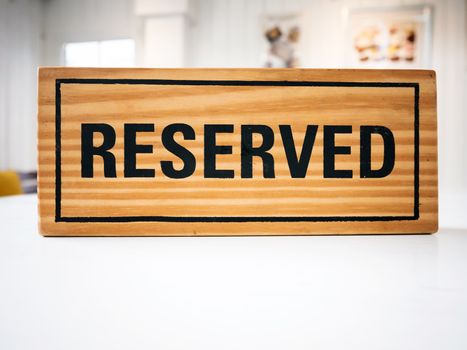 Reservation seat at restaurant for dating on celebrate day concept. Restaurant with reserved wooden sign on white table with cafe decorate places setting and evening light with bokeh for dinner time