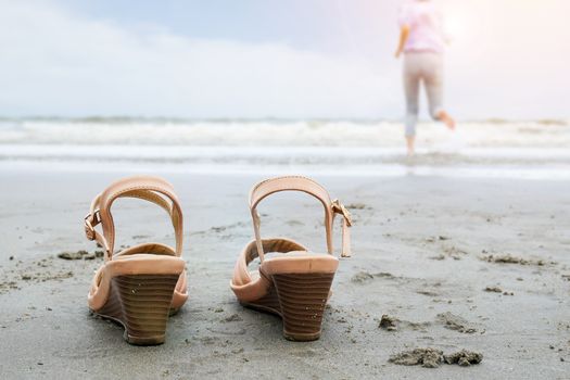 Beach holidays travel vacation lifestyle concept - Happy middle aged business woman take off shoe run into the sea with barefoot enjoying beautiful beach.