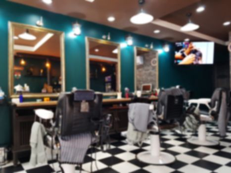 Interior of a beauty and hair salon blurry background concept. Row of black leather chairs in modern barber shop interior.