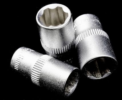 Three Wrench inserts, blurred and with strict illumination, black background