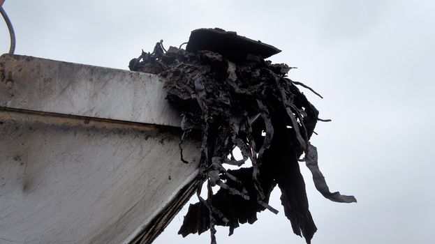 Adhesive black waste on the excavator shovel, excavation from a pit on the site of a construction project