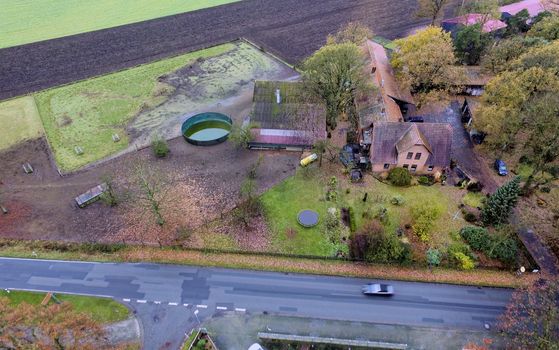 Aerial view of a farm in Germany with an asphalt road in the foreground