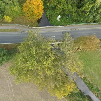 Aerial photograph of a country road crossing the course of an ugly straightened stream, made by drone