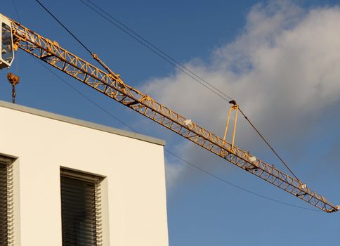 crane boom in front of a bright blue sky above the corner of a new building, abstract