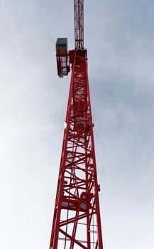 Red high construction crane on a building site, oblique picture of an abstract image effect, dramatic sky.