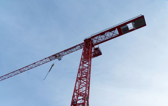 Red high construction crane on a building site, oblique picture of an abstract image effect, dramatic sky.