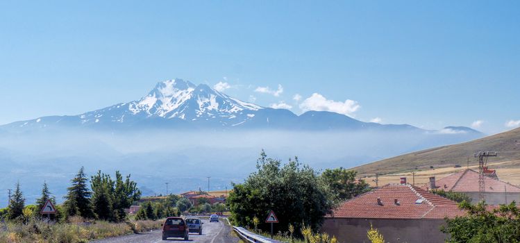 Volcano Erciyes from a distance with a fog bank underneath the summit, Anatolia, Turkey, from the driving car