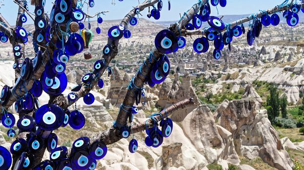 Many blue glass eyes (Nazar Boncugu) as a defence against the evil eye, at a branch in front of the mountains of Cappadocia