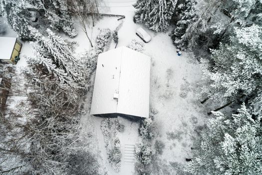 Family house in a forest after the first snowfall, aerial view with drone