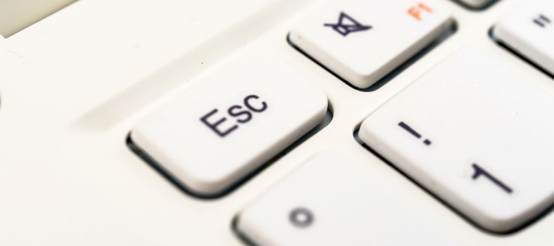 Macro recording of the escape character on a white laptop keyboard, abstract escape concept