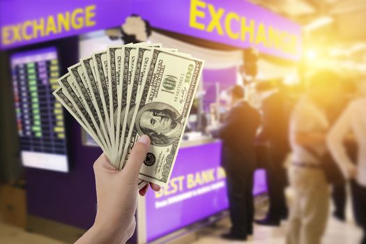people, withdrawal, saving, finance, currency conversion and money exchange concept - hands with US dollar money with blur exchange booth background