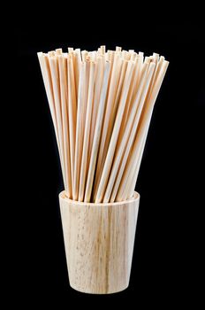 Wheat straw for drinking water in wooden glass on black background. Zero waste concept.