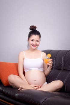 Pregnant woman eating food with ingredient for healthy concept : Asian young  pregnant woman hold fresh orange juice in glass with smile friendly face. Beautiful Asia model in her 20s