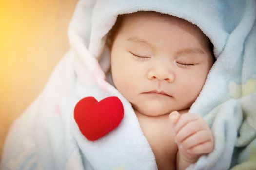 Family love relationship concept : red heart shaped put on sleep cute Asian baby. Lovely newborn Asia infant model female in her first year