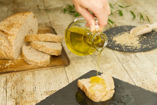 Closeup of woman hands pouring extra virgin olive oil from an am