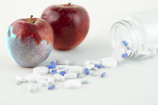 Concept: human GMO manipulation of nature and relative poisoned fruits. Close-up of an apple contaminated by changing color from the medicines in front of it on a white background