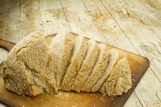 Close-up of a sliced loaf of homemade bread with sesame seeds o