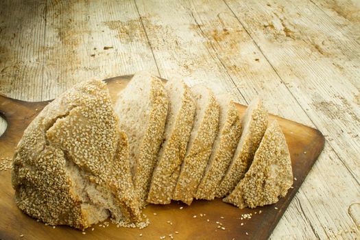Close-up of a sliced loaf of homemade bread with sesame seeds o