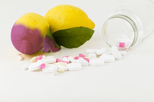 Concept: human GMO manipulation of nature and relative poisoned fruits. Close-up of a lemon contaminated by changing color from the medicines in front of it on a white background