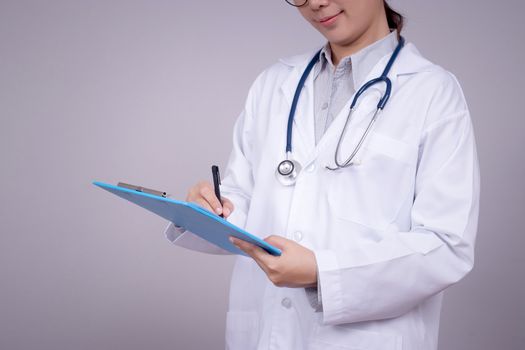 Healthy concept : Young Asian doctor writing on clipboard  for patient chart , anonymous face. Beautiful Asia female model in her 30s