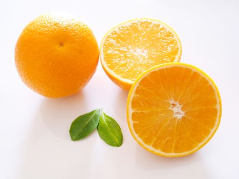 Close up of bright citrus orange fruits with half orange and green leaf isolated on white background.