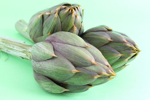 Raw spiny artichokes isolated on green background