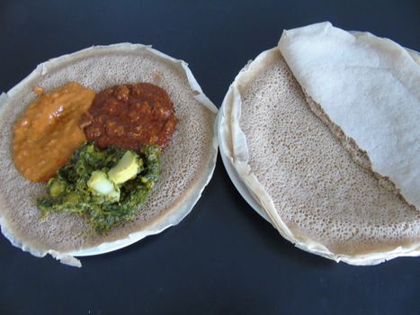 Asmara, Eritrea - 08/05/2020: Ethiopian and Eritrean food, assortment of main dishes. Injera is a sourdough flatbread made from teff flour. It is the national dish of Ethiopia, Eritrea.