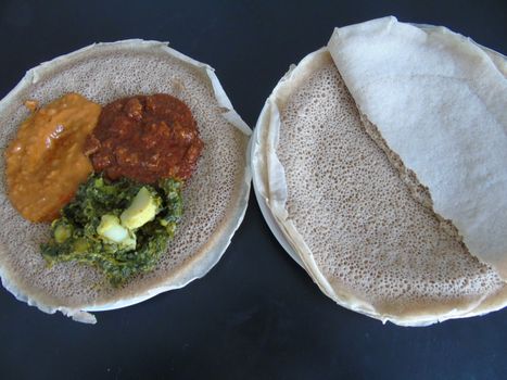 Asmara, Eritrea - 08/05/2020: Ethiopian and Eritrean food, assortment of main dishes. Injera is a sourdough flatbread made from teff flour. It is the national dish of Ethiopia, Eritrea.