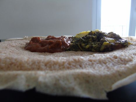 Asmara, Eritrea - 08/05/2020: Ethiopian and Eritrean food, assortment of main dishes. Injera is a sourdough flatbread made from teff flour. It is the national dish of Ethiopia, Eritrea.