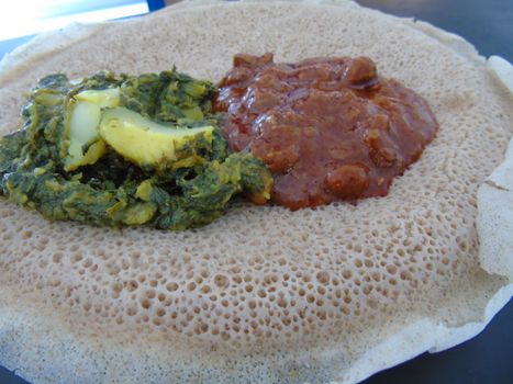 Asmara, Eritrea - 08/05/2020: Ethiopian and Eritrean food, assortment of main dishes. Injera is a sourdough flatbread made from teff flour. It is the national dish of Ethiopia, Eritrea.