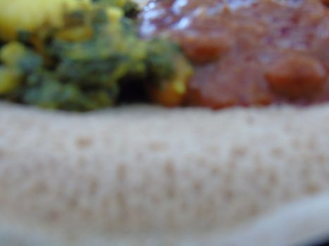 Asmara, Eritrea - 08/05/2020: Ethiopian and Eritrean food, assortment of main dishes. Injera is a sourdough flatbread made from teff flour. It is the national dish of Ethiopia, Eritrea.