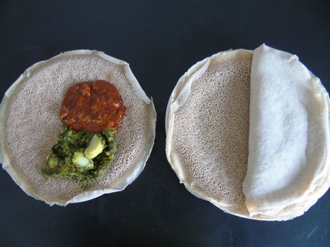 Asmara, Eritrea - 08/05/2020: Ethiopian and Eritrean food, assortment of main dishes. Injera is a sourdough flatbread made from teff flour. It is the national dish of Ethiopia, Eritrea.