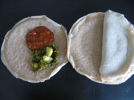 Asmara, Eritrea - 08/05/2020: Ethiopian and Eritrean food, assortment of main dishes. Injera is a sourdough flatbread made from teff flour. It is the national dish of Ethiopia, Eritrea.